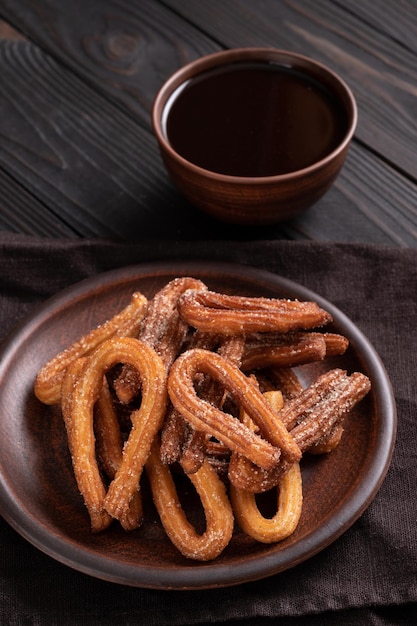 Homemade churros with chocolate on a dark wooden rustic background