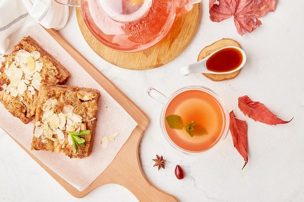 Foto torta di dessert a cannella e mela fatta in casa e teiera di vetro con una tazza di tè di legno di mirtillo estetico