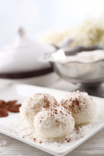 Homemade coco sweets on plate, on light background