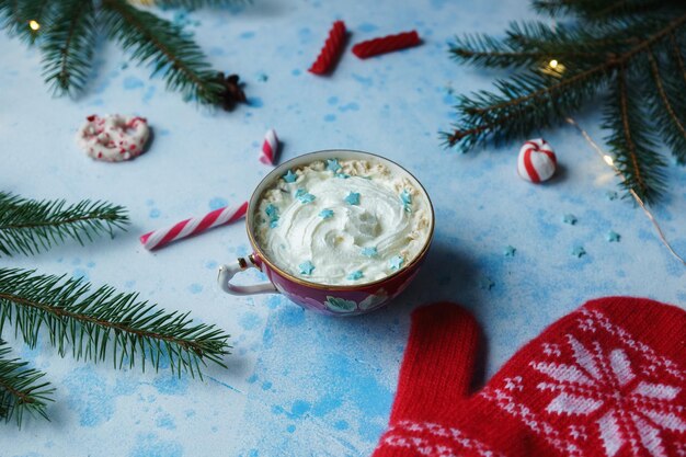 写真 自家製のココアまたはホット チョコレート クリーム モミの木のキャンディーと青いコンクリート背景に赤いミトン クリスマスや新年の飲み物居心地の良い家の装飾の選択と集中