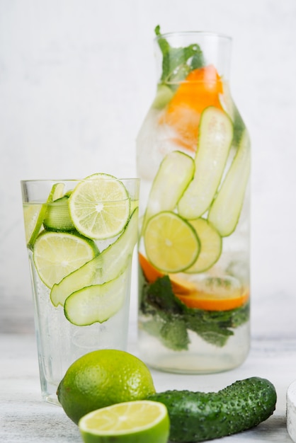 Homemade cold lemonade with lemon, lime, cucumber and mint on a white background.