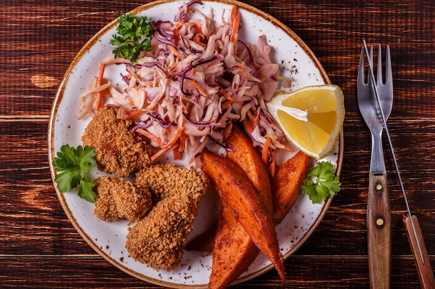 Homemade cooked chicken nuggets, sweet potatoes and coleslaw