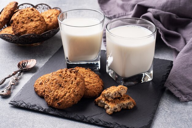 Homemade cookies cereals oats and a glass of milk on the grey concrete table.