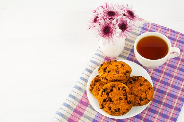 Homemade cookies and cup of tea on checkered napkin