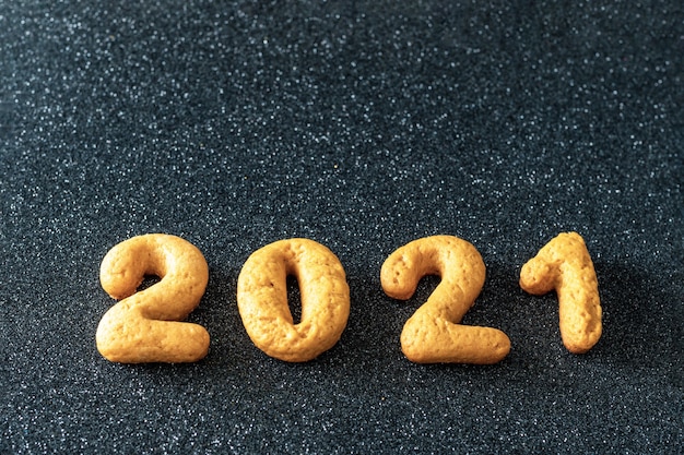 Homemade cookies in the form of numbers 2021 on a black background. Christmas food background