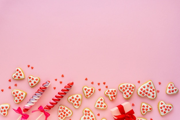 Homemade cookies in the shape of hearts with lollipops on pink
