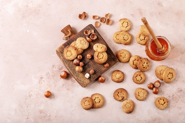 Homemade cookies with hazelnuts served with honey on white texture background