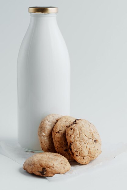 Homemade cookies with pieces of chocolate on the background of a bottle of milk on a white background