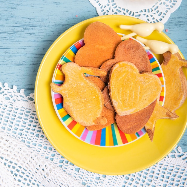 Homemade cookies on a yellow plate with knitted lace tablecloth on a kitchen table