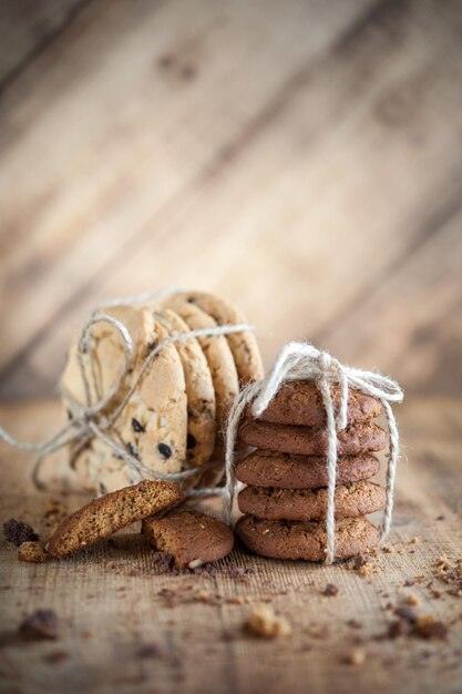 Homemade corded wholegrain cookies with oatmeal, linen and sesame seeds and traditional american cookies with chocolate chips on dark rustic wooden table . Healthy vegan food concept.