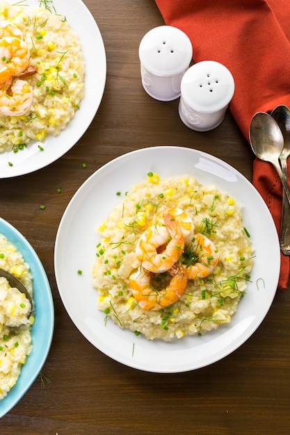 Homemade corn risotto with roasted shrimp on dining table.