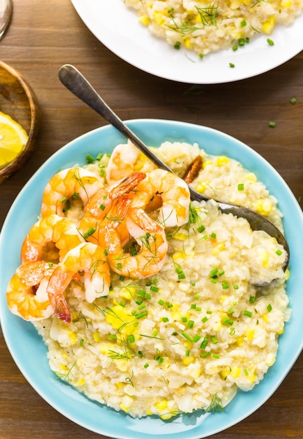 Homemade corn risotto with roasted shrimp on dining table.