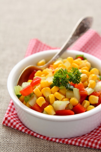 Homemade corn salsa in white bowl with spoon