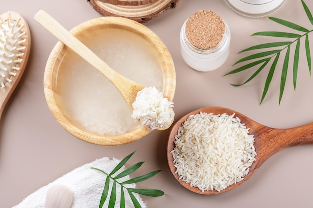 Homemade cosmetic rice water with ingredients and beauty kit on beige background top view home spa flat lay