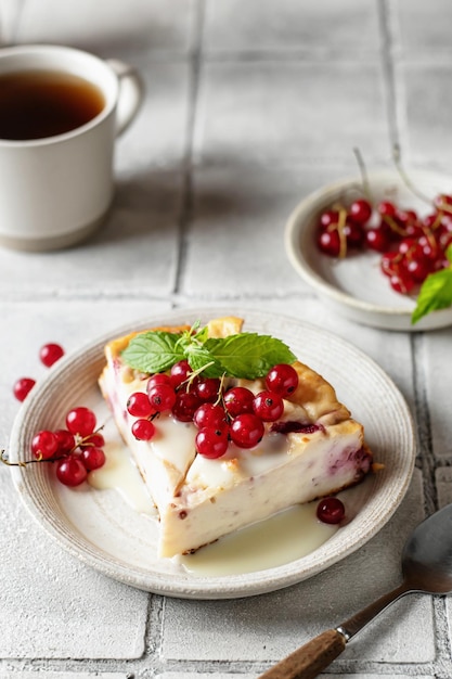 Homemade cottage cheese casserole garnished with sauce redcurrant and cup of coffee on gray tile background