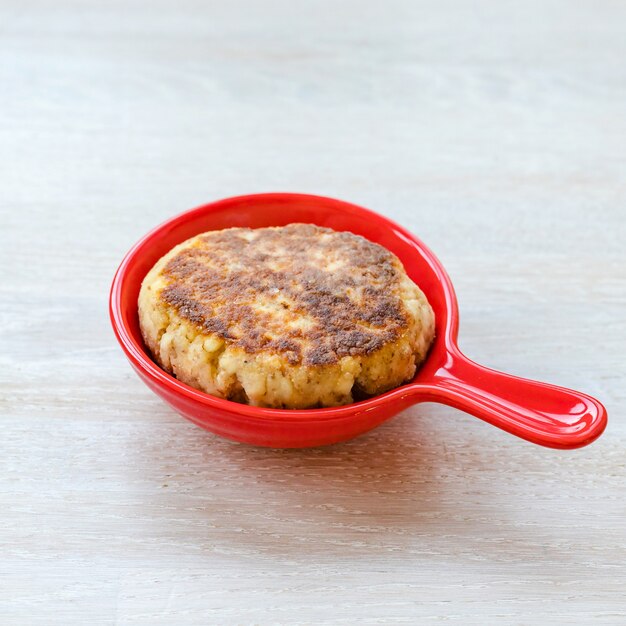 Homemade cottage cheese pancakes syrniki stack on red ceramic pan on white table. Close up. Selective focus. Copy space