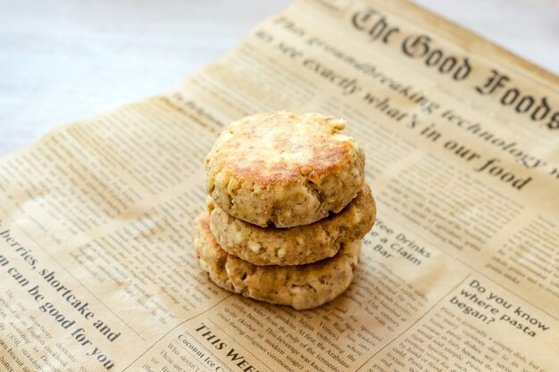 Homemade cottage cheese pancakes syrniki stack on retro baking paper newspaper on white table. close up. selective focus. copy space