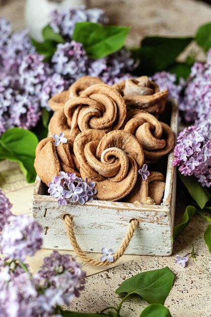 Homemade cottage cheese shortbread cookies shape rose in a rustic wooden box Cozy still life with lilac flowers