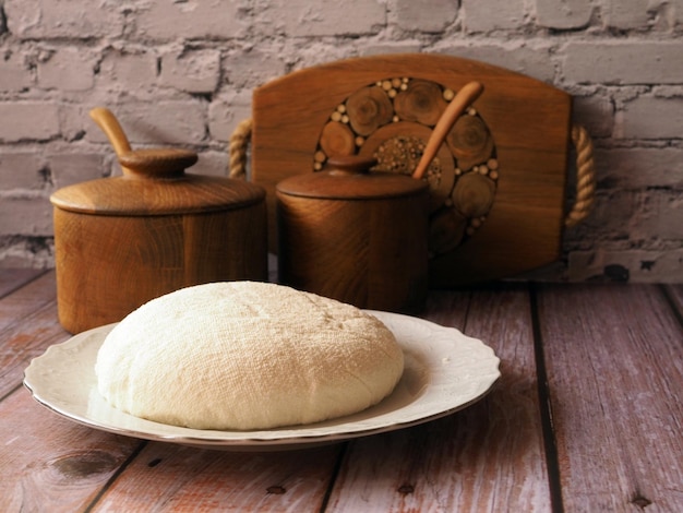 Homemade cottage cheese on a white plate Wooden background