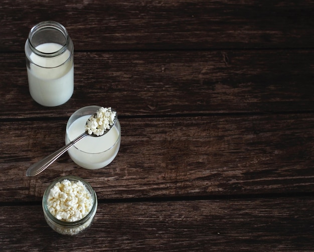 Foto ricotta fatta in casa con kefir in un bicchiere di vetro con un cucchiaio su uno sfondo di legno