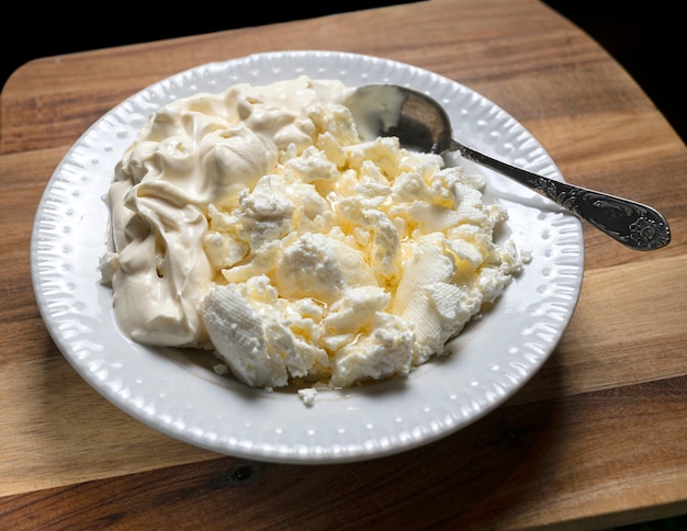 Homemade cottage cheese with sour cream on a wooden board