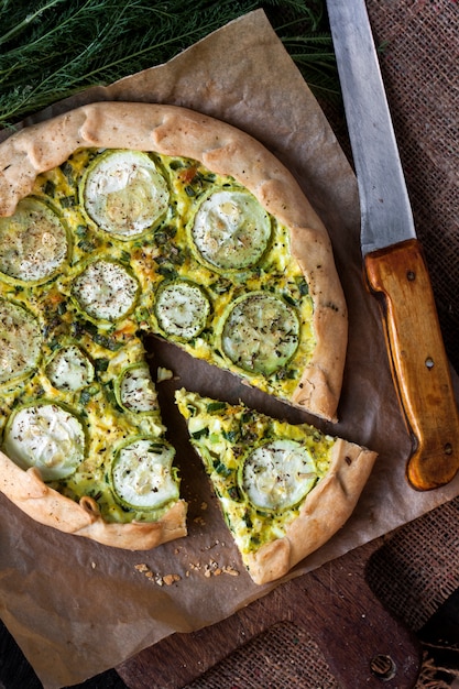 Homemade courgette and goat cheese pie on a dark rustic wooden board surface