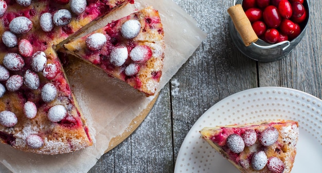 Homemade cranberry pie with walnuts, berries and powdered sugar. Top view. Space for text. Rustic style. Selective focus.