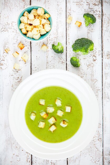 Homemade cream soup with broccoli and croutons on wooden background