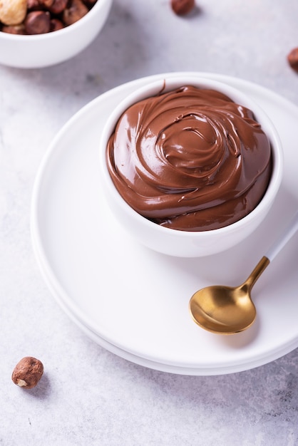 Homemade cream with hazelnuts and cocoa on light table, selective focus image