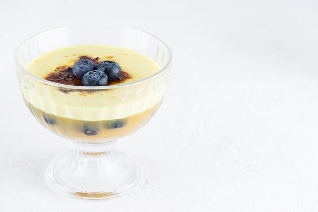 Homemade creme brulee with jelly and blueberries in a glass bowl