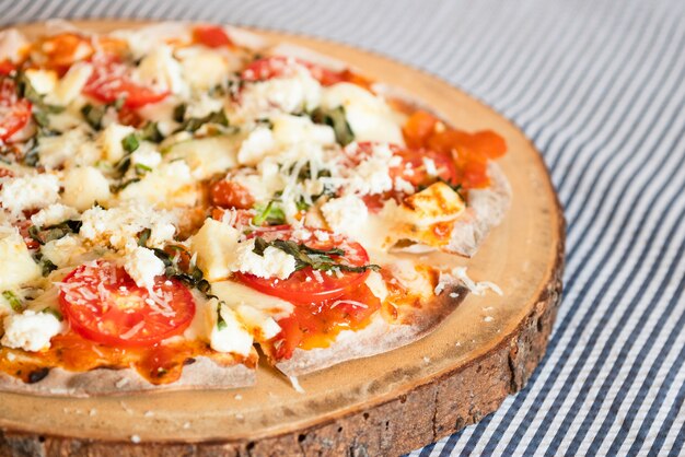 Homemade crispy pizza on piece of wood, cozy kitchen style 