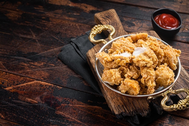 Homemade crispy popcorn chicken bites in a skillet wooden\
background top view copy space