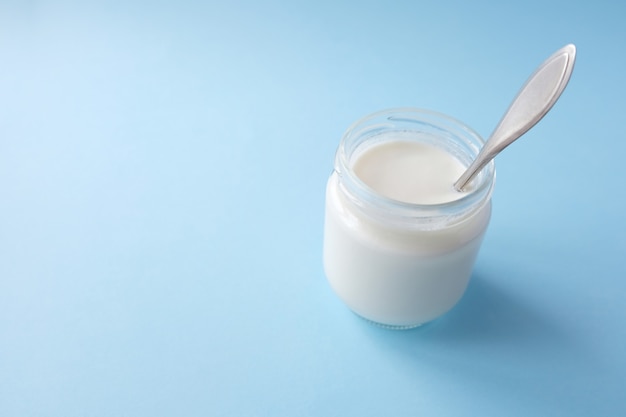 Homemade crockpot greek yogurt in glass jars on light blue background. Selective focus, copy space.