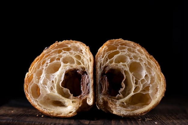 Croissant fatto in casa tagliato a metà su sfondo nero