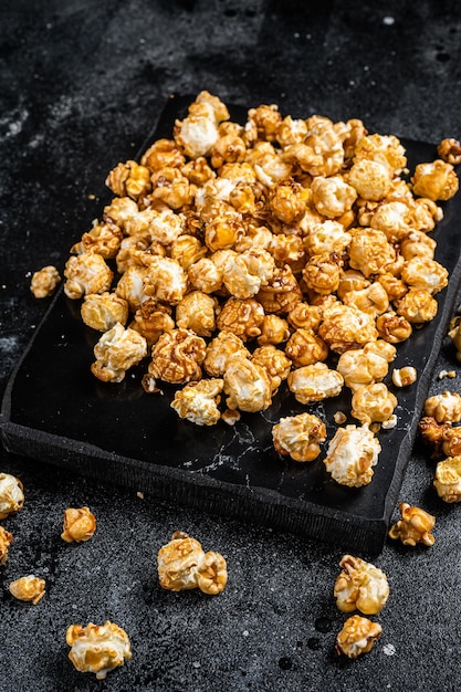 Homemade Crunchy Caramel Popcorn on marble board. Black background. Top view.