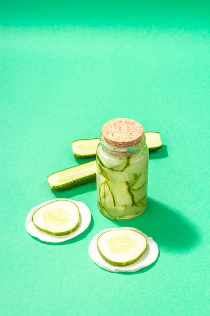 Homemade cucumber cosmetics. Detoxification skin vegetable masks. Natural face lotion or and tonic water. Trendy hard light, dark shadow, turquoise background, copy space