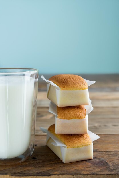 Homemade cupcakes with glass of milk on wooden table with blue background. Copy space. Vertical photo. Handmade madeleines.