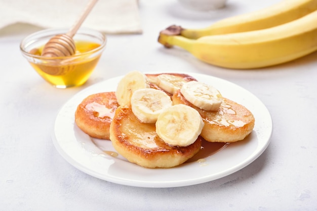 Homemade curd cheese pancakes with banana slices and honey