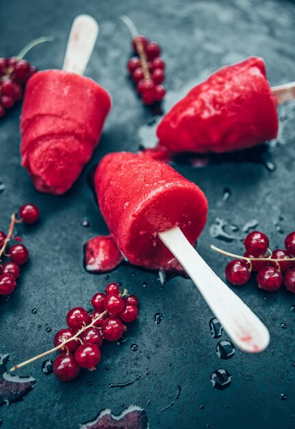 Homemade currant popsicles and red currants on slate