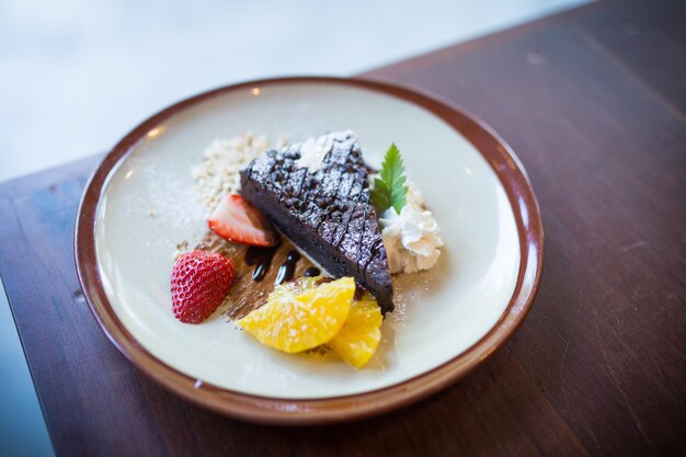 Homemade dark chocolate brownies and strawberry and fresh orrange