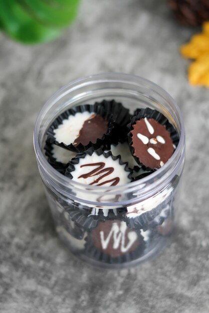 Homemade dark chocolate and white cup on a clear jar chocolate cup with grey background