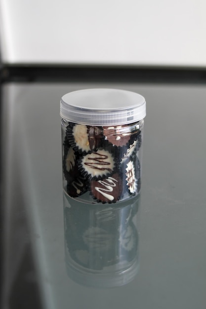 Homemade dark chocolate and white cup on a clear jar chocolate cup with grey background