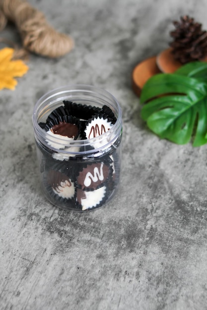 Homemade dark chocolate and white cup on a clear jar chocolate cup with grey background