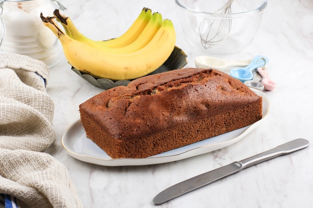 Foto deliziosa torta di banane fatta in casa con pane sul tavolo bianco chiaro, concetto di bianco da forno con copia spazio per il testo