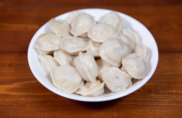 Homemade delicious boiled dumplings in a white plate on a wooden table