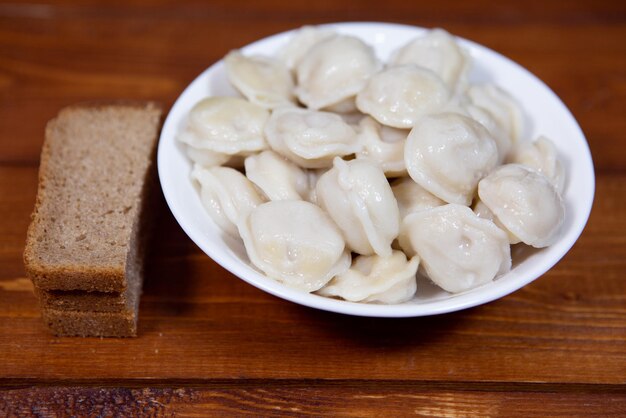 나무 탁자에 있는 하얀 접시에 집에서 만든 맛있는 삶은 만두