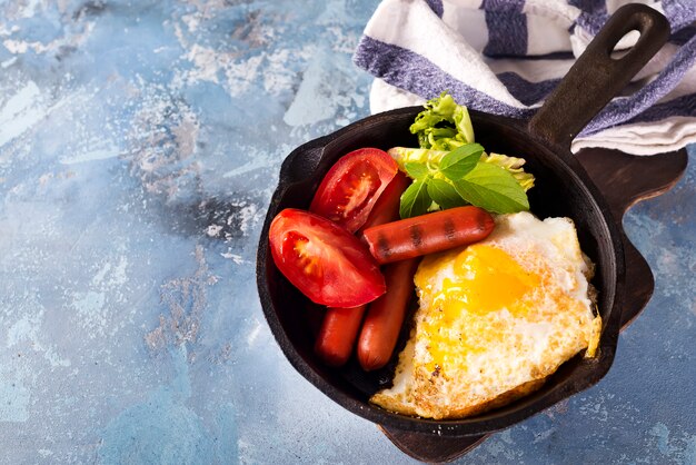 Homemade delicious breakfast on a pan with fried egg, toast, sausage, vegetable, black coffee