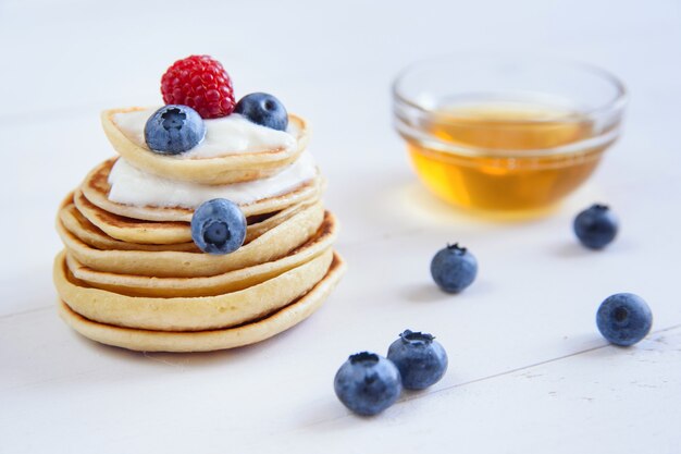 Homemade delicious pancakes with yogurt, fresh blueberries, raspberries and honey . Concept of tasty and healthy food.