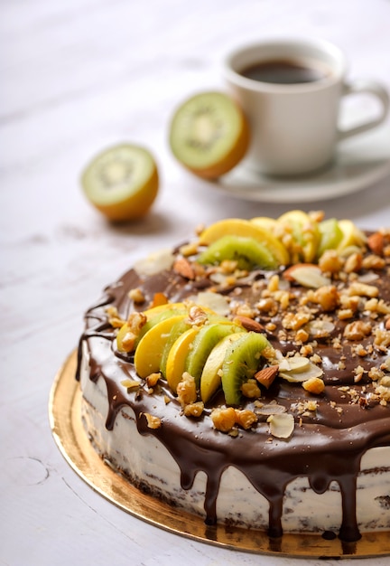 Homemade delicious sweet cake with fruits, chocolate, apple, kiwi on cup of coffee americano