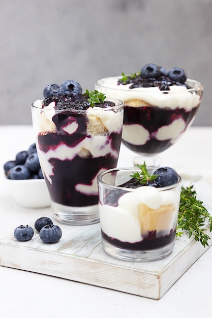 Homemade dessert in glasses with blueberries, cream and ladyfingers